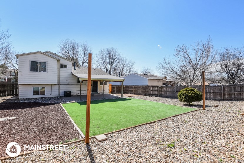a backyard with a lawn and a white house