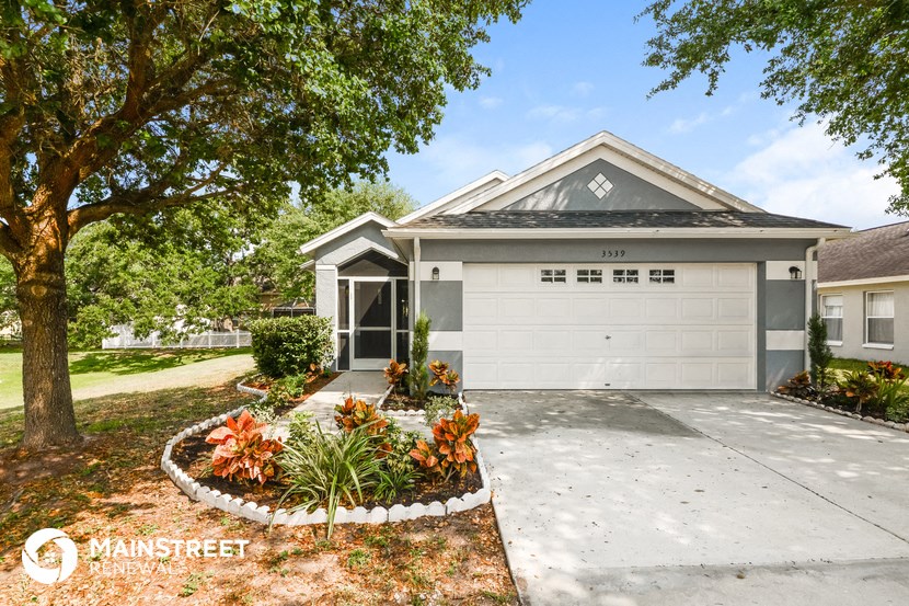 a home with a white garage door and a driveway with a tree