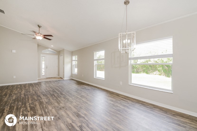 the living room of a new home with a large window and a ceiling fan