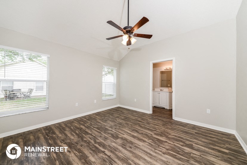 the spacious living room with wood flooring and a ceiling fan