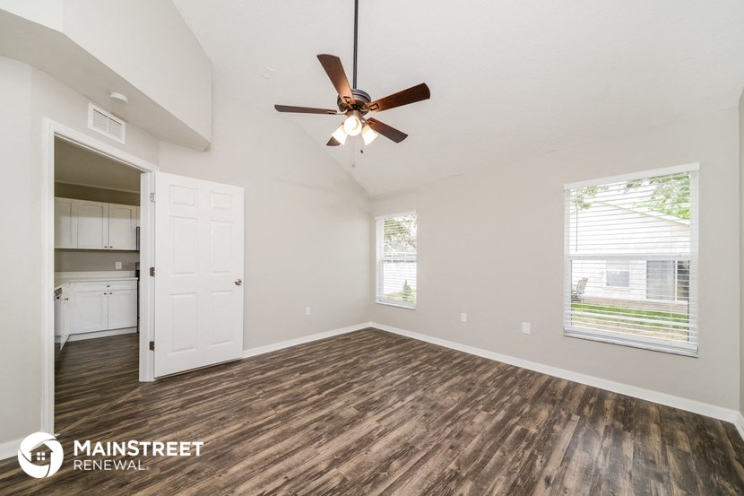 the spacious living room with a ceiling fan and a door to the kitchen