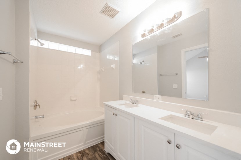 a white bathroom with two sinks and a tub and a mirror