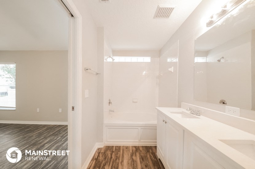 a bathroom with white cabinets and a shower and a sink