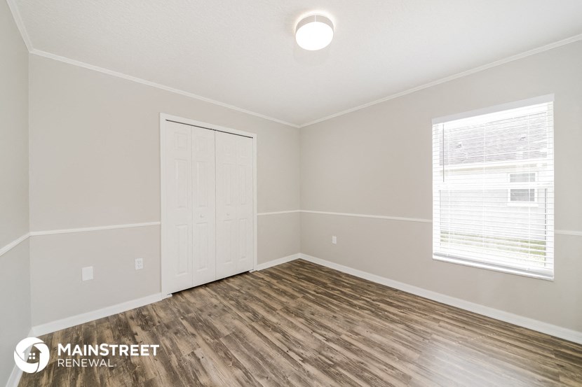 the spacious living room with wood flooring and white walls