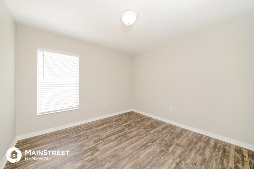 the spacious living room with hardwood flooring and a window