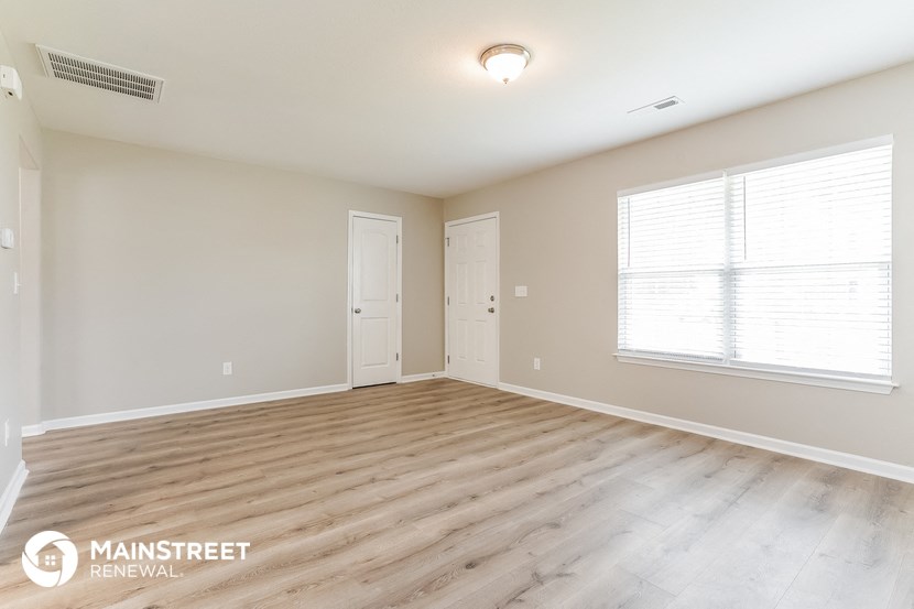 the spacious living room with wood flooring and a large window