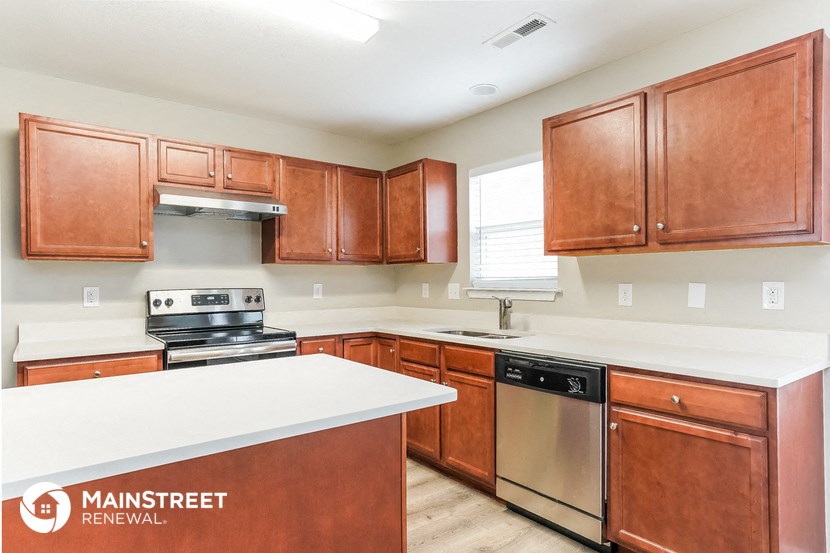 a kitchen with wooden cabinets and a white counter top