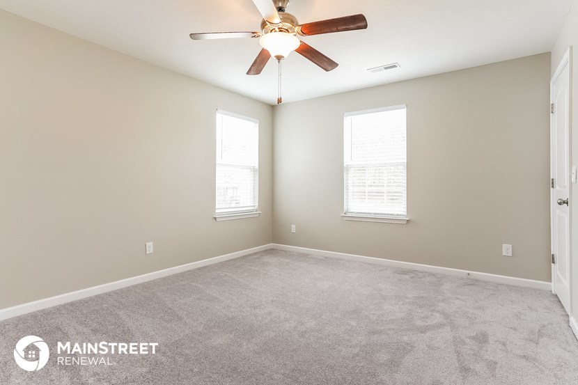 the spacious living room with carpeting and a ceiling fan