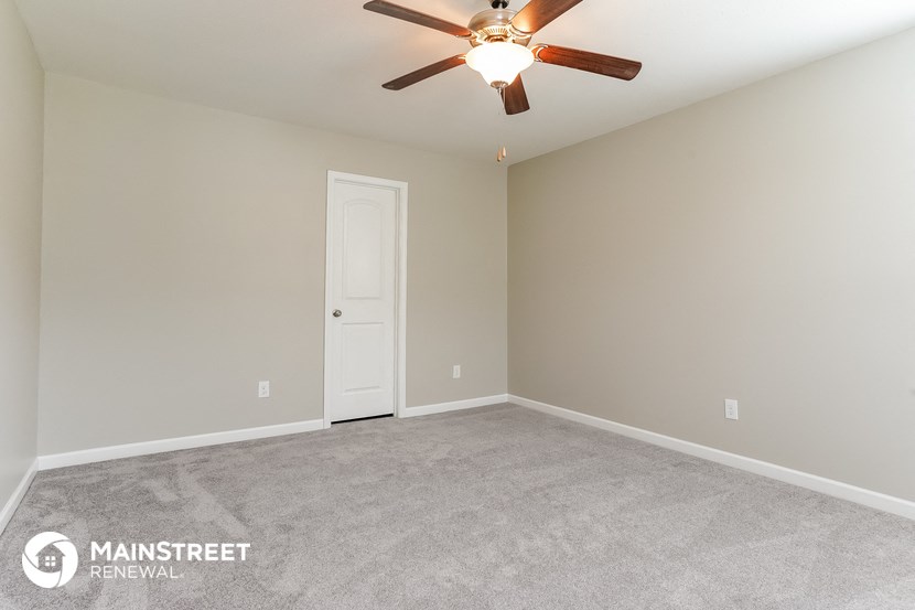 the spacious living room with carpeting and a ceiling fan