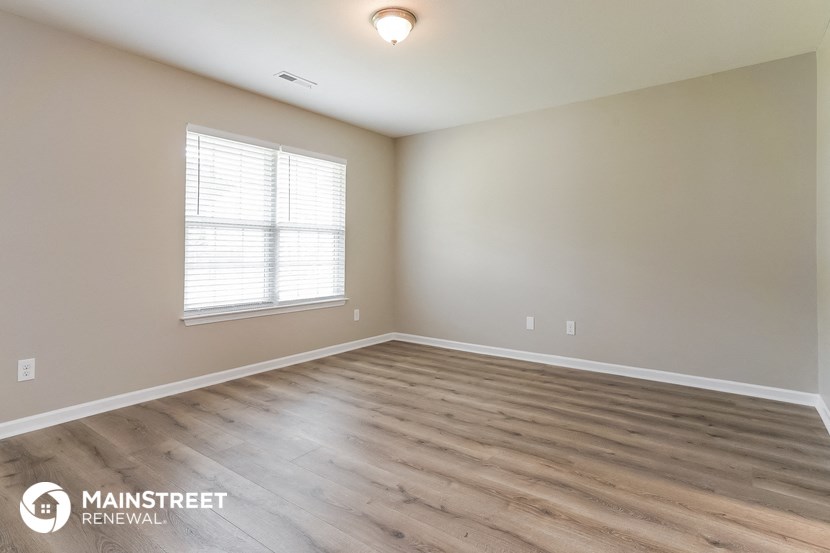 the spacious living room with wood flooring and a window