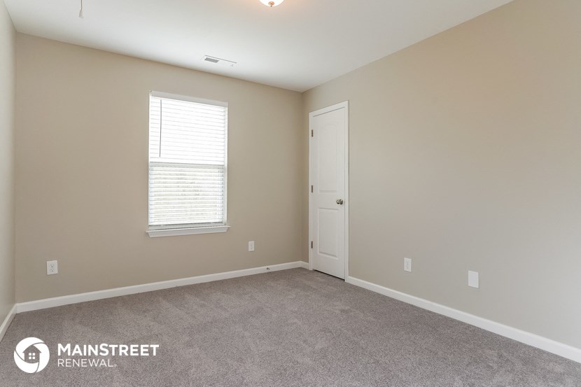 the spacious living room with carpeted flooring and a white door