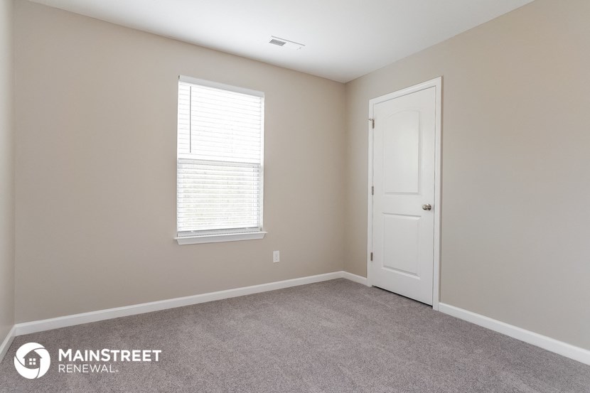 a bedroom with a door and a window and a carpeted floor