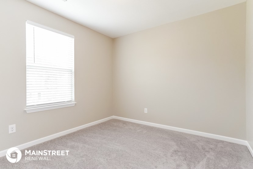 the upstairs bedroom has a carpeted floor and a window