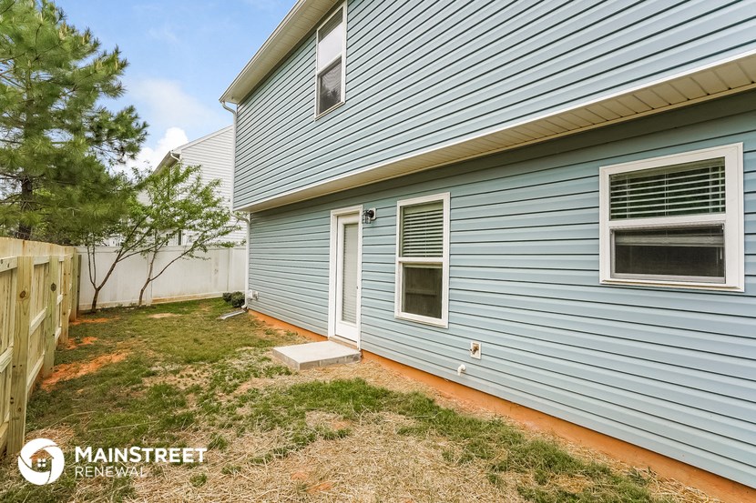 a blue house with a yard and a white fence