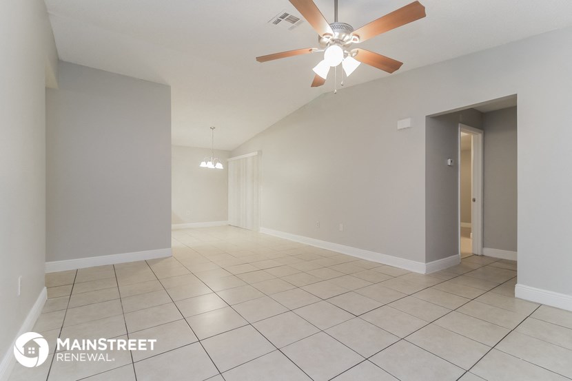the spacious living room with tile flooring and a ceiling fan