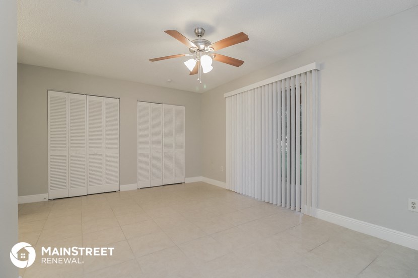 an empty living room with a ceiling fan and blinds