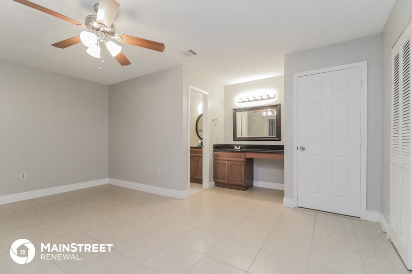 a large living room with a white tile floor and a white door to the bathroom