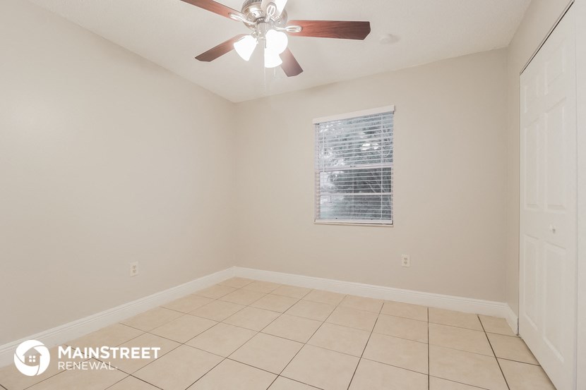 the living room has a tile floor and a ceiling fan