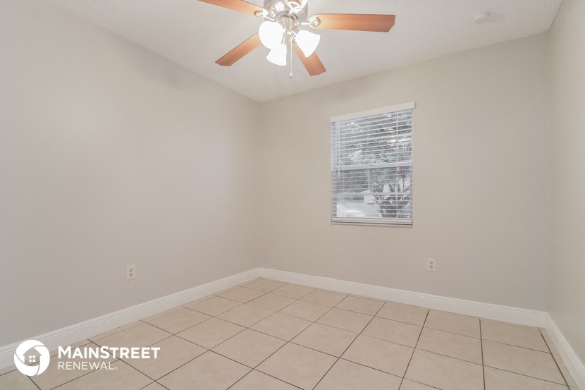 the living room has a ceiling fan and a tiled floor