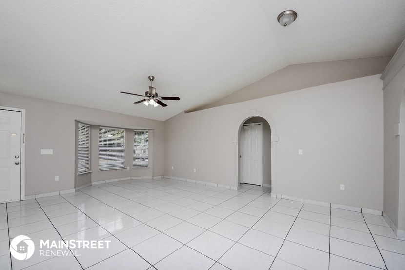 an empty living room with a ceiling fan