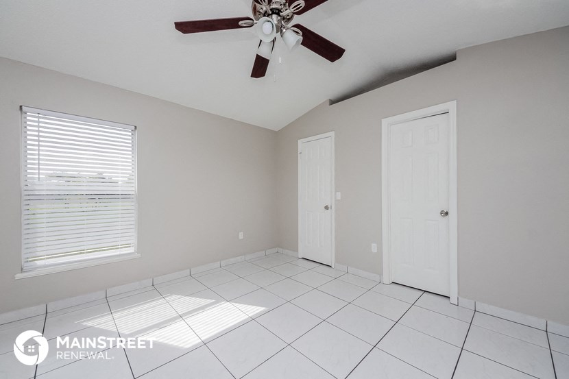 a clean and empty room with a ceiling fan and white tiles