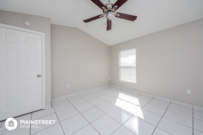 an empty room with a ceiling fan and a white tile floor