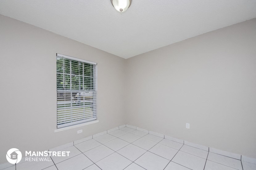the spacious living room with a window and white tile flooring