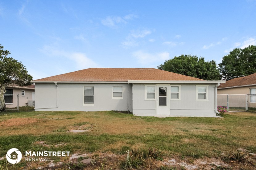 the front of a small white house with a grassy yard