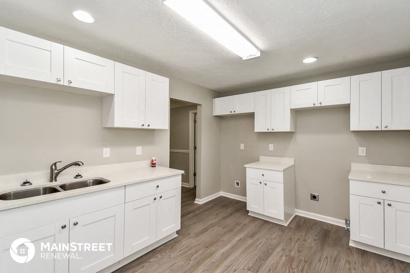 the kitchen of an apartment with white cabinets and a sink