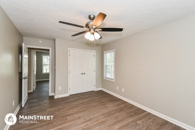 the living room is spacious and has a ceiling fan