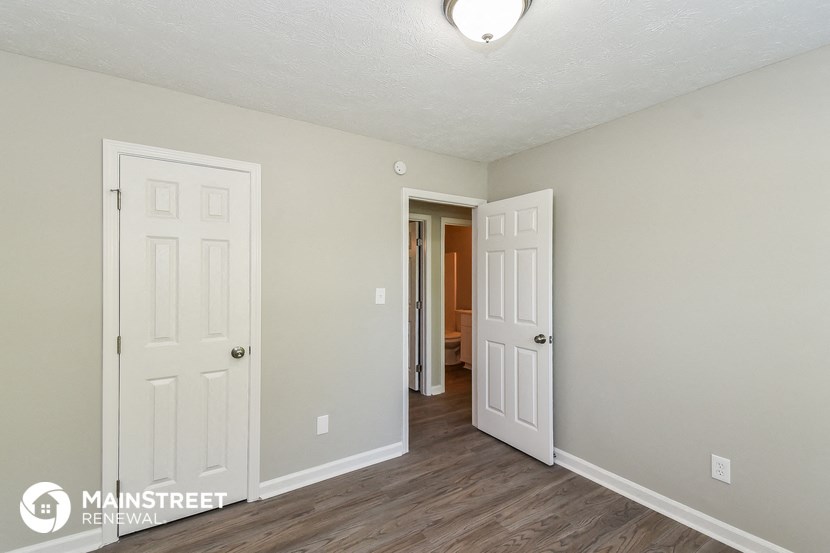 the living room of an apartment with two doors and a hallway