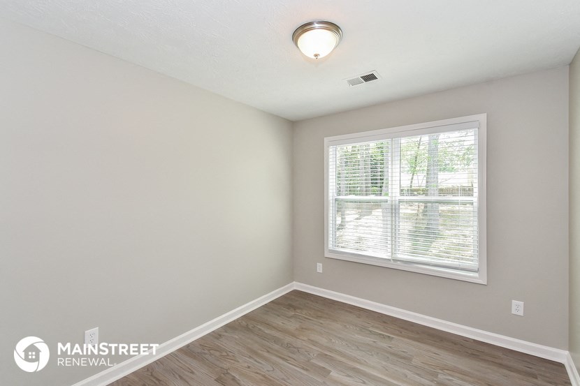 the spacious living room with wood flooring and a large window