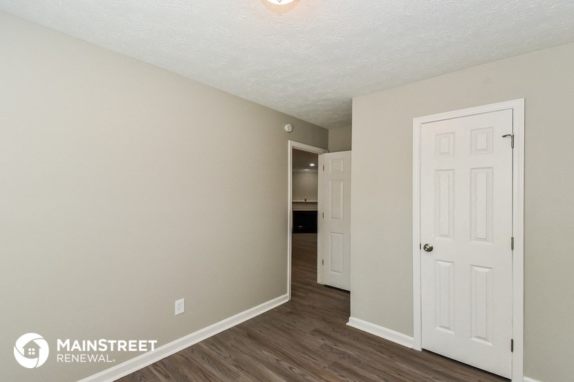 the living room of an apartment with a door to the hallway and a closet