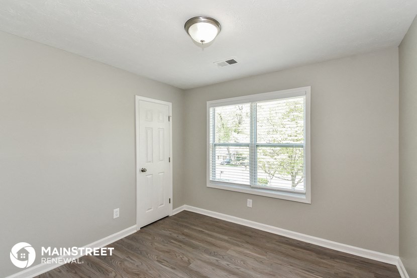 the spacious living room with a large window and wood flooring