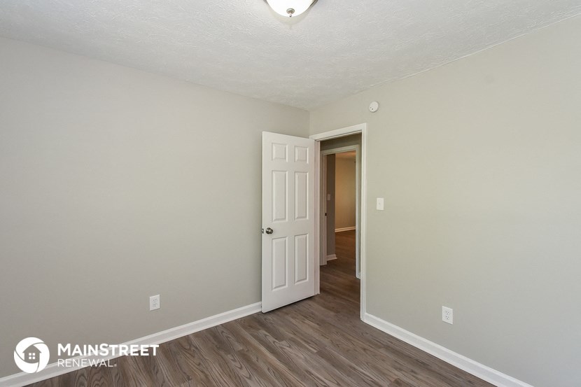 the living room of an apartment with wood flooring and a white door