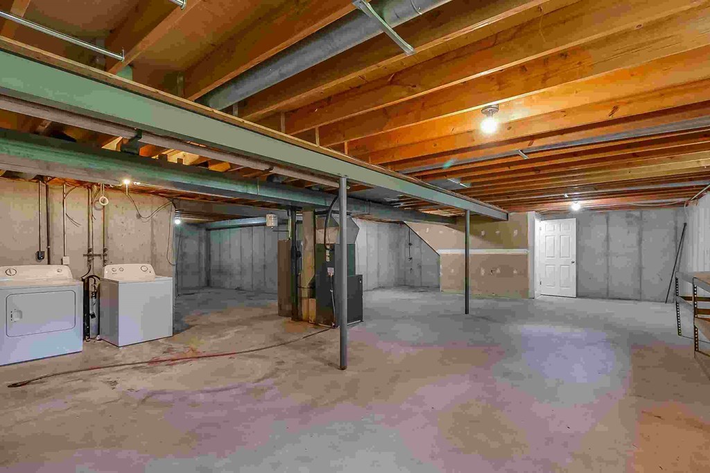 A room with wooden ceiling and walls, and a concrete floor with a purple stain.