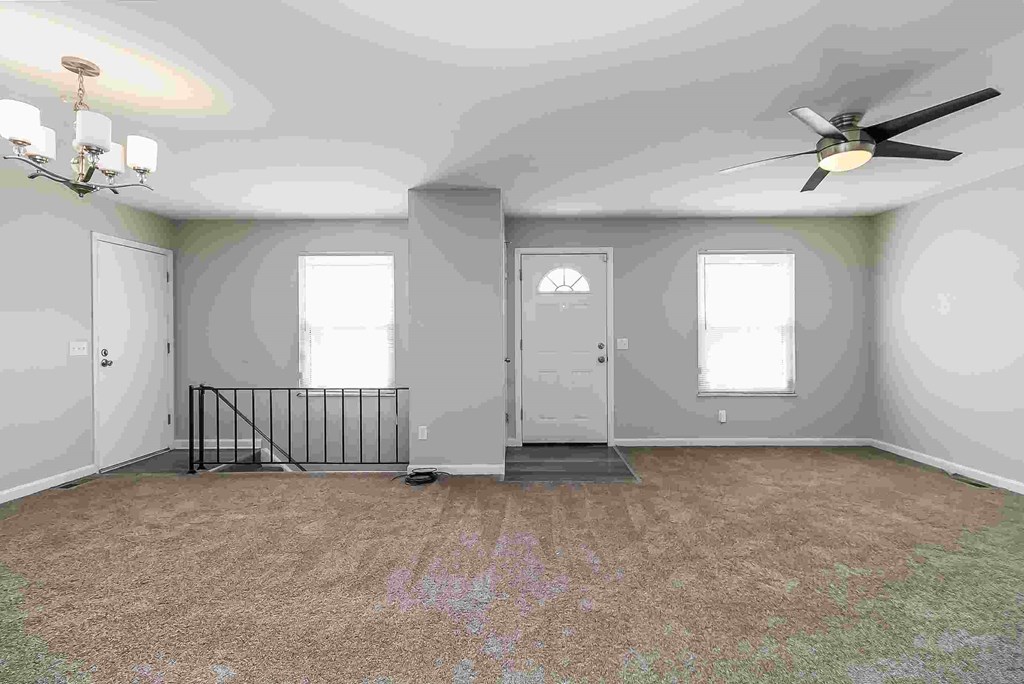 A room with a ceiling fan and a rug on the floor.