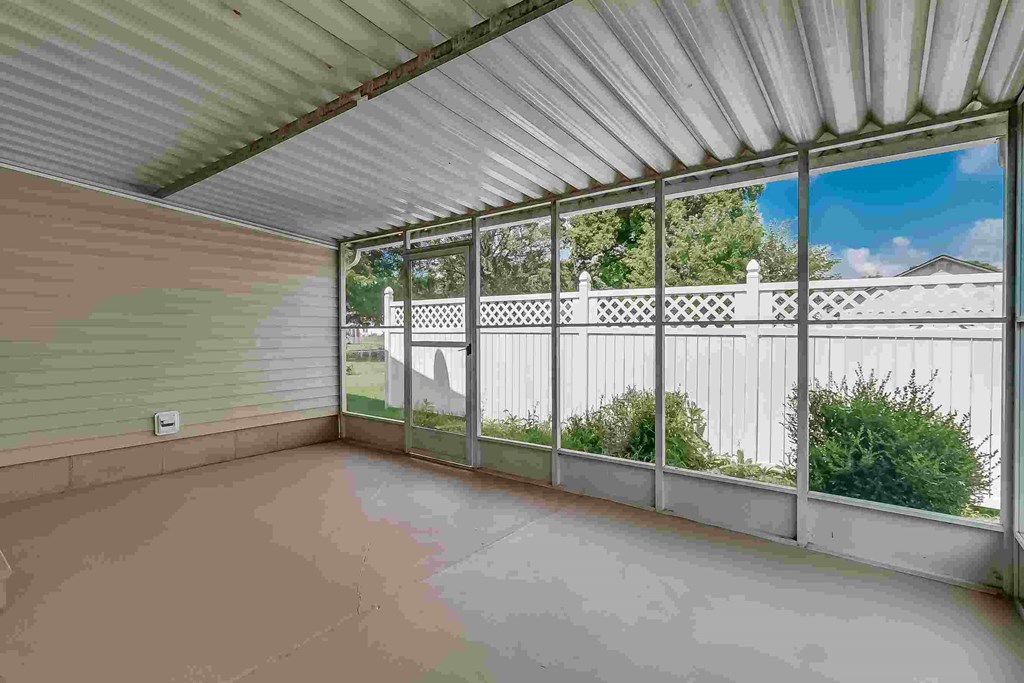 A patio with a white fence and a green wall.