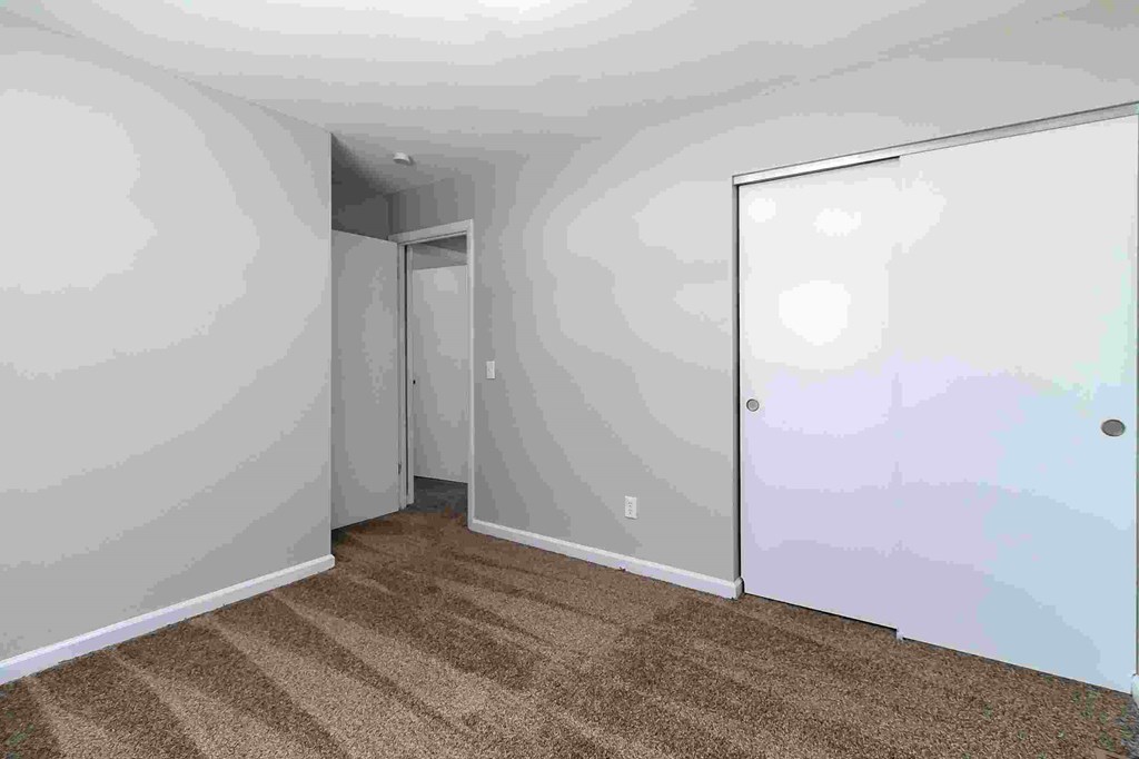 A room with a carpeted floor and a door.