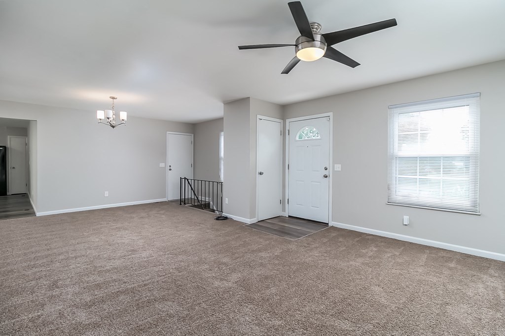 A spacious room with a ceiling fan and carpeted floor.