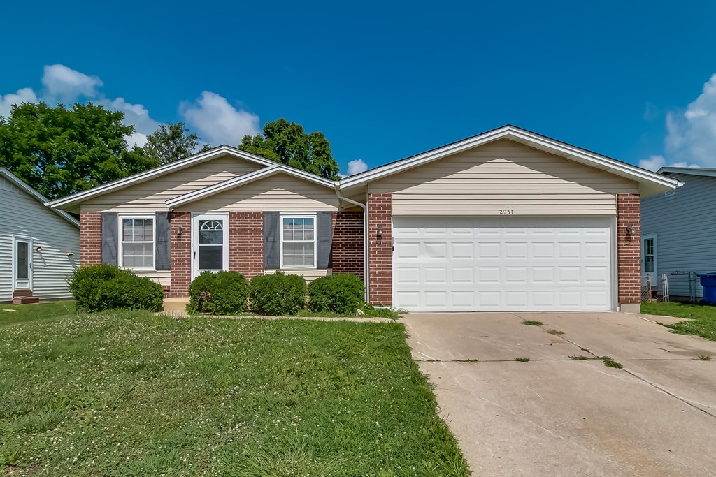 A house with a white garage door and brick pillars.