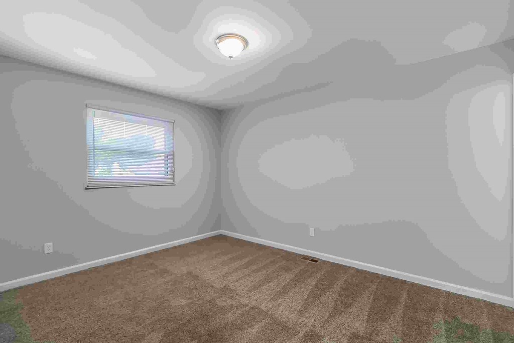 A room with a carpeted floor and a window.