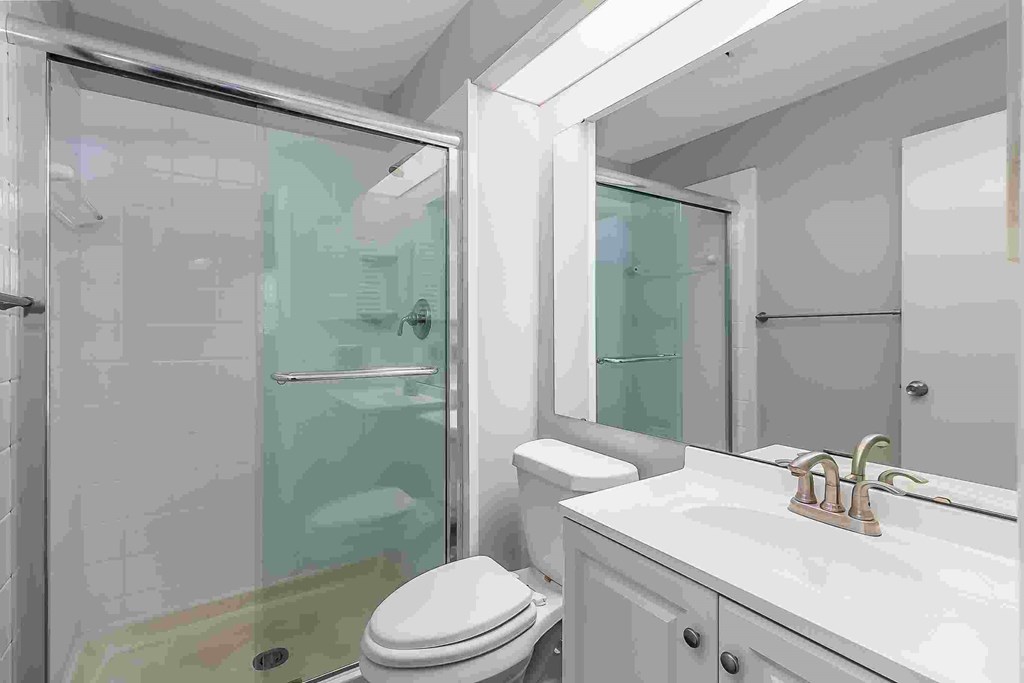 A white bathroom with a toilet, sink, and shower.