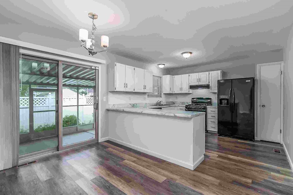 A modern kitchen with a white island and wooden flooring.