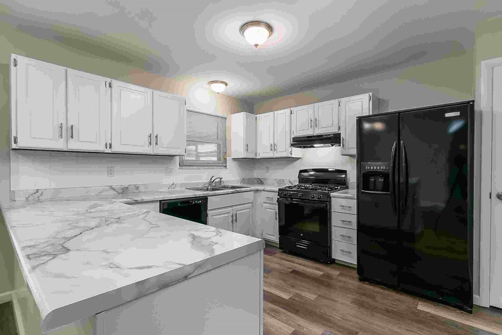 A kitchen with black appliances and white cabinets.