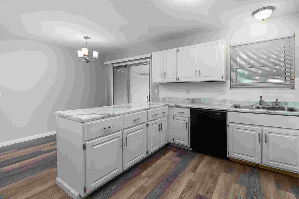 A kitchen with white cabinets and a black dishwasher.