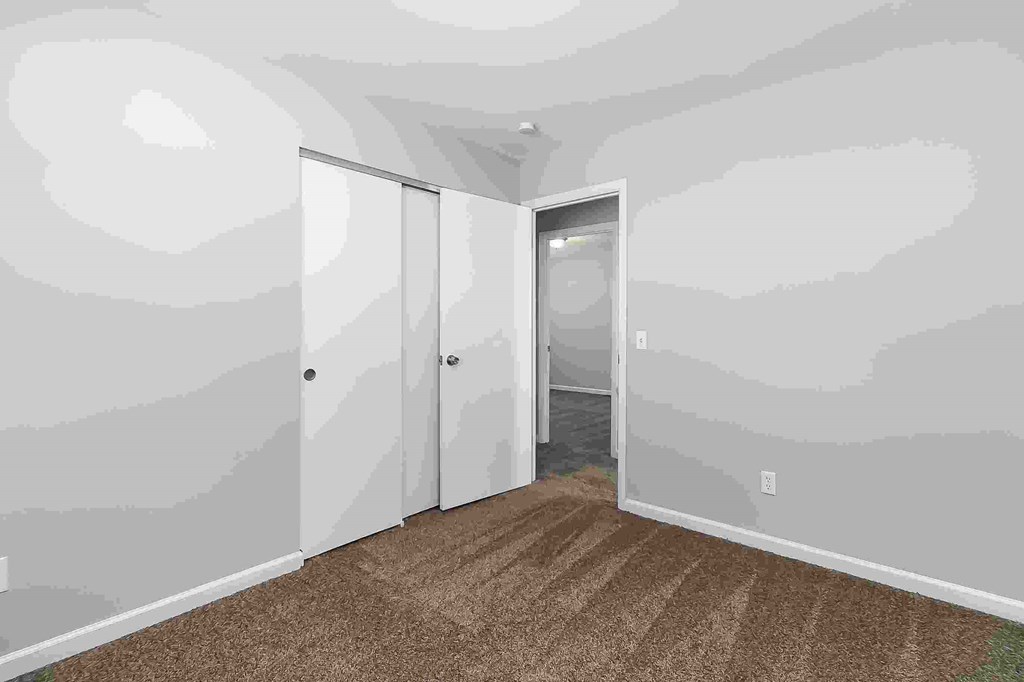 A room with a carpeted floor and a wall with a grey paint job.