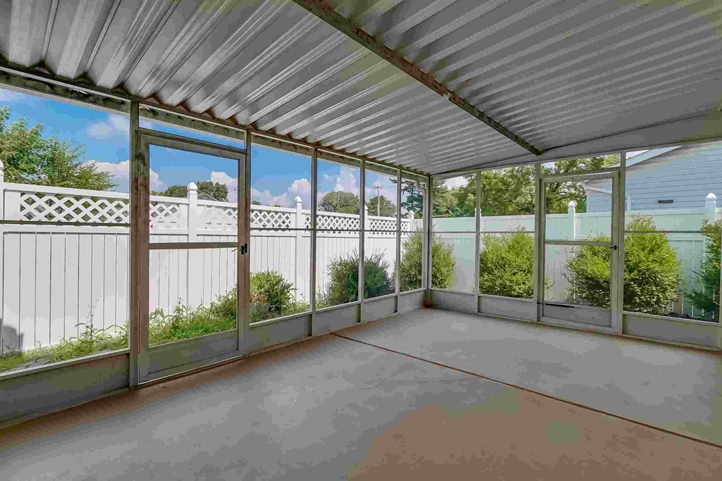 A sunroom with a white ceiling and a glass wall.