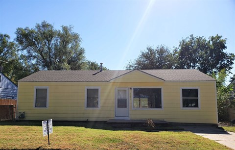 A yellow house with a sign in front of it.