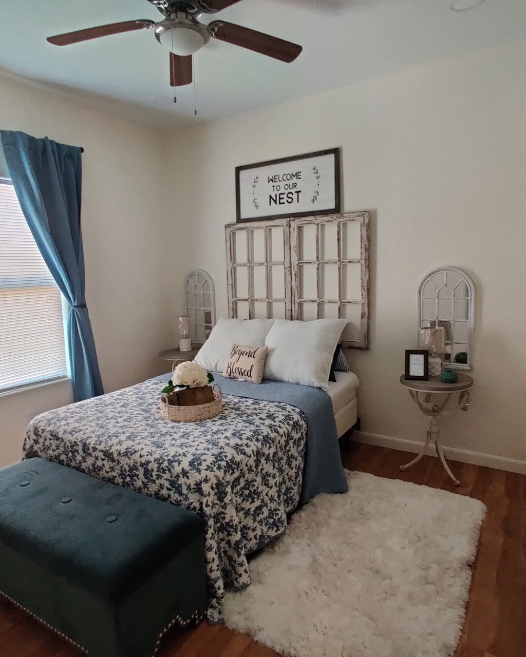 a bedroom with a bed and a blue and white bedspread and a ceiling fan